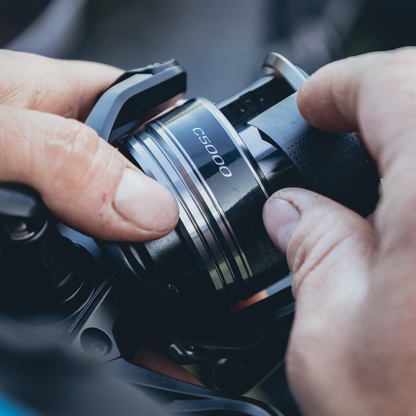 Hands adjusting the Shimano Aero BB C5000 reel, highlighting its precision-engineered components and user-friendly design.