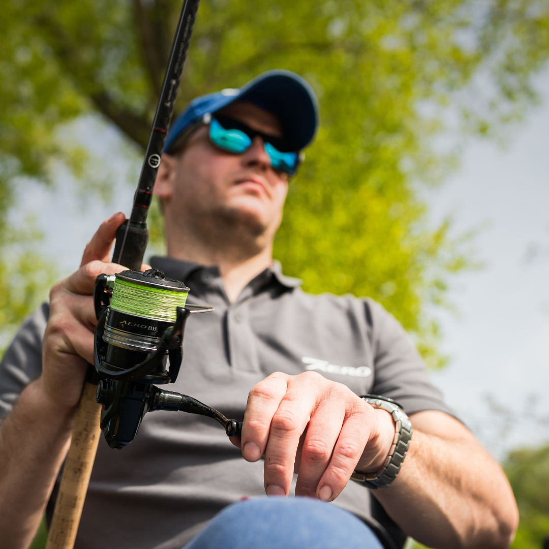 Angler seated outdoors, holding a rod equipped with the Shimano Aero BB C5000 reel, ready for a fishing session.