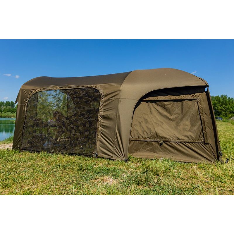 FOX Frontier X Deluxe Extension System 150x260x155cm in khakigrün, featuring a spacious camping tent with mesh windows and durable fabric, set up on grassy terrain near a lake.