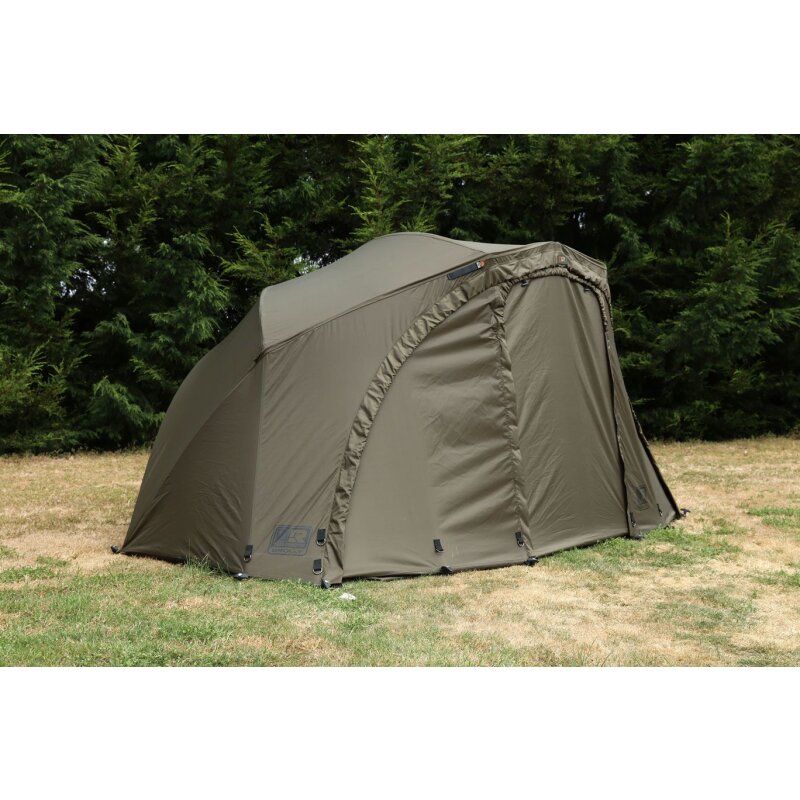 FOX R-Series Brolly System in green, set up on grass with a backdrop of trees. Ideal for camping and outdoor shelter.